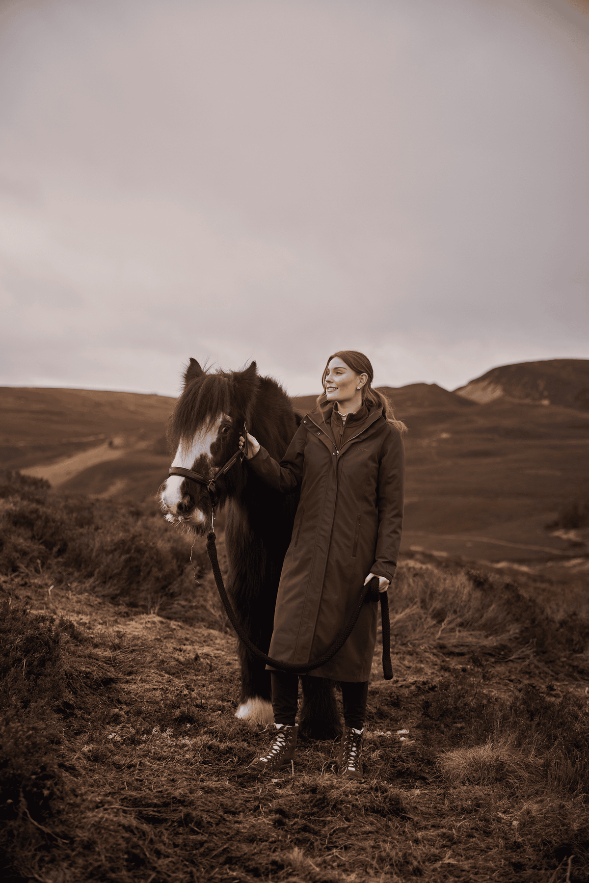 Woman wearing the Schöffel Marefield Coat while walking with a horse in the British countryside.