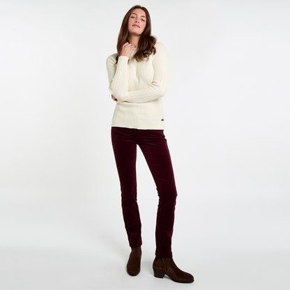 Woman wearing Dubarry Honeysuckle Pincord Trousers in Raisin with a cream knitted jumper and brown ankle boots.