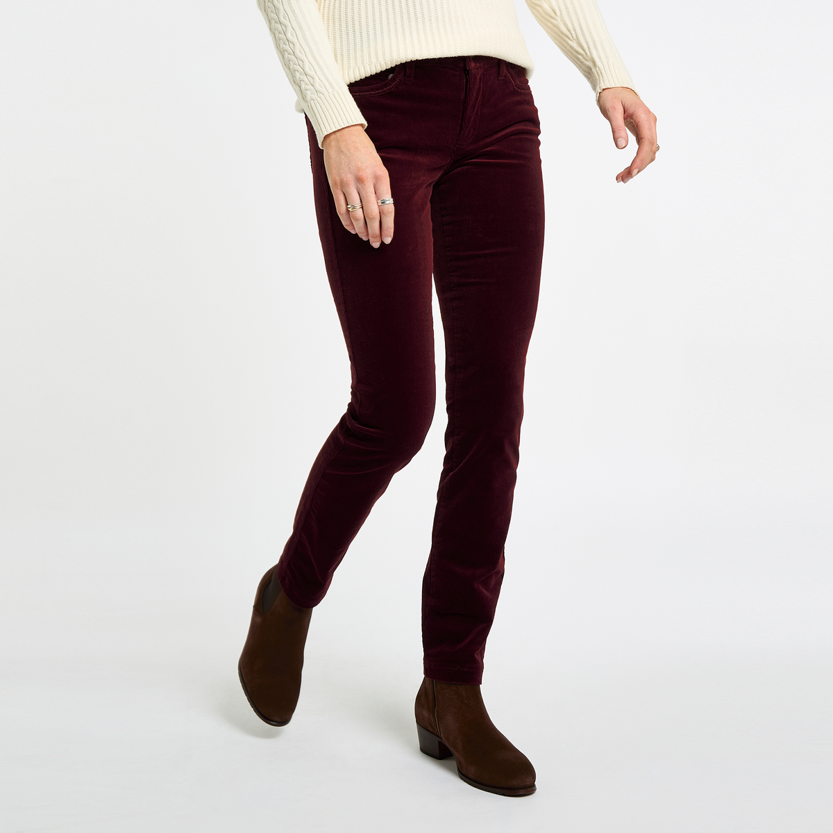 Woman wearing Dubarry Honeysuckle Pincord Trousers in Raisin with brown ankle boots, shown walking to highlight the slim-leg fit.