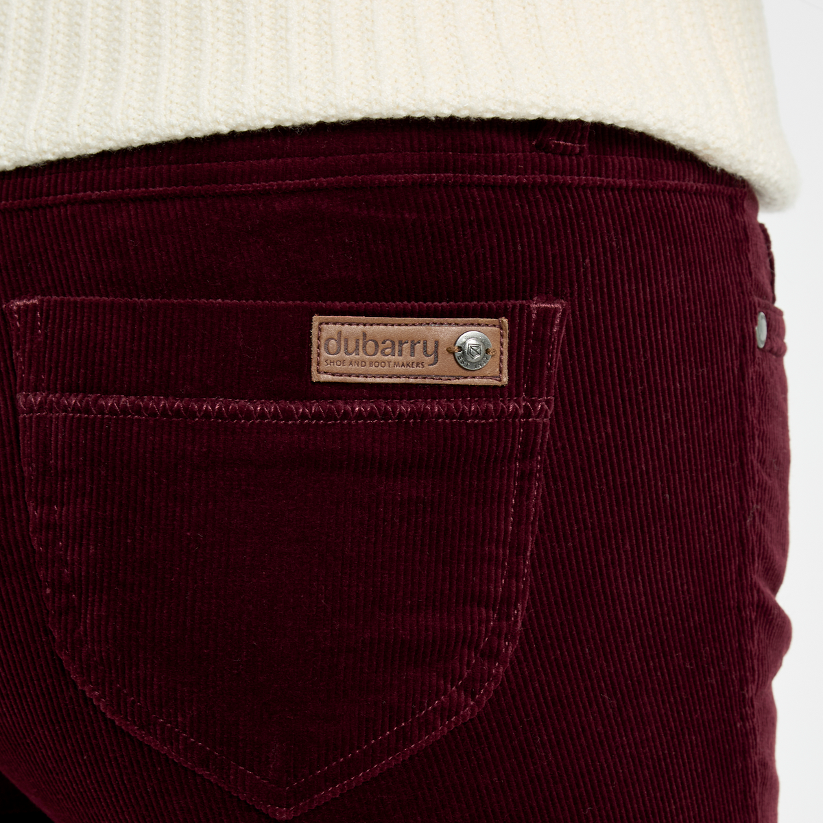 Close-up of Dubarry Honeysuckle Pincord Trousers in Raisin, showing the rear pocket, fine cord texture and leather logo badge.
