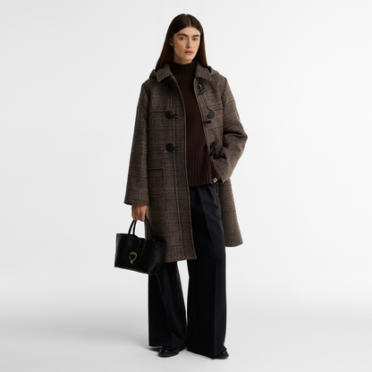 Model wearing the Barbour Melody Check Duffle Coat in brown with an all-over Prince of Wales check. The coat is open to showcase the zip, concealed behind a traditional duffle coat toggle fastening. 