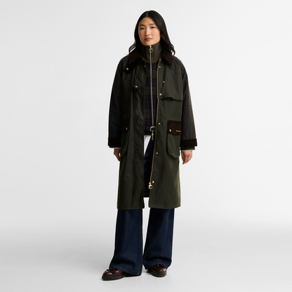 Model wearing the Barbour Kirklees Check Waxed Jacket. A longline waxed cotton jacket in fern green featuring a dark brown corduroy trim on the collar, cuffs and pocket flaps.
